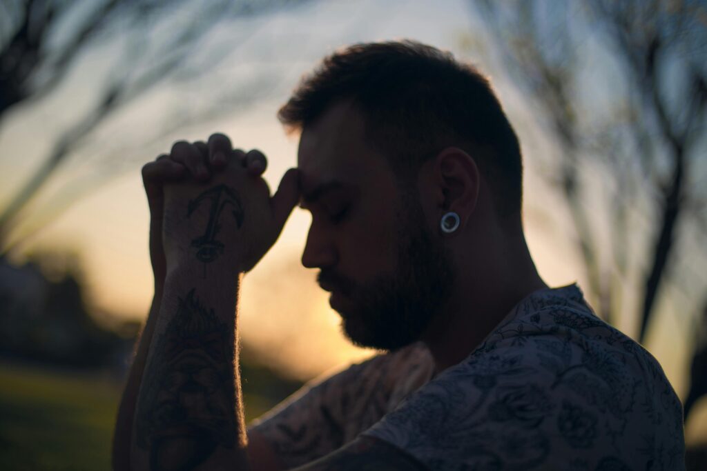 Profile of a tattooed man in serene contemplation at sunset.